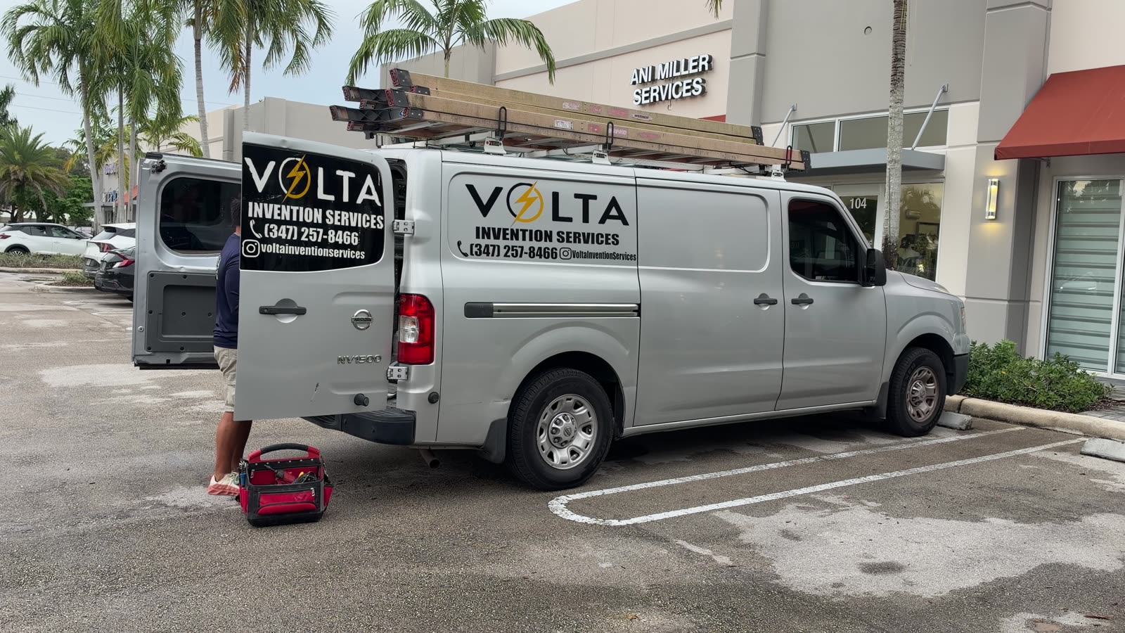 Volta Invention Services work van with ladders on the roof, parked outside a job site